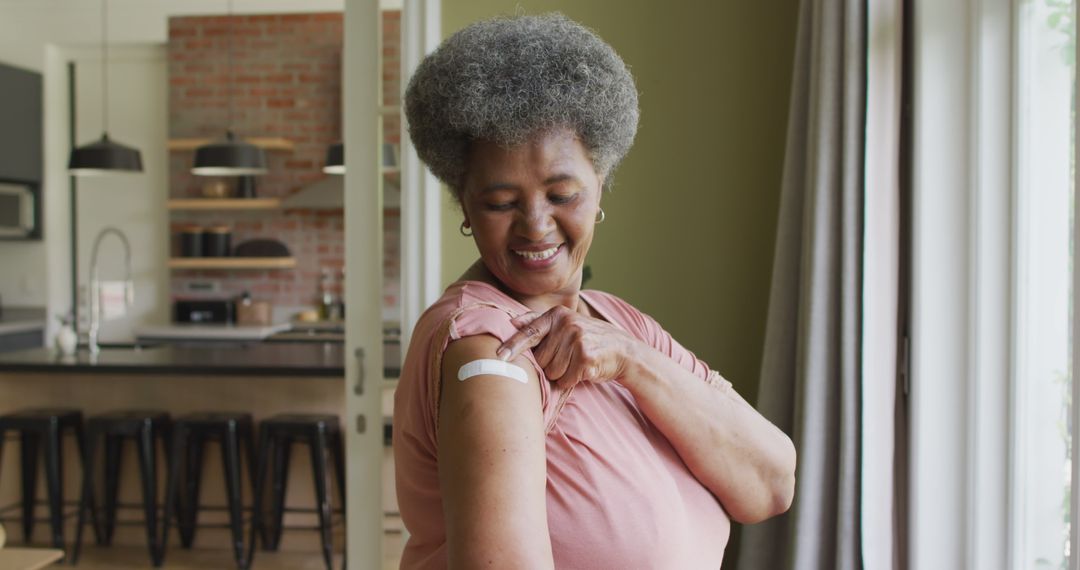 Senior Woman Proudly Displays Vaccination Bandage in Living Room - Free Images, Stock Photos and Pictures on Pikwizard.com