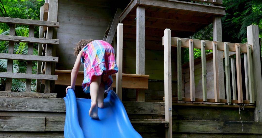 Child Climbing Up Slide of Wooden Playhouse in Yard - Free Images, Stock Photos and Pictures on Pikwizard.com