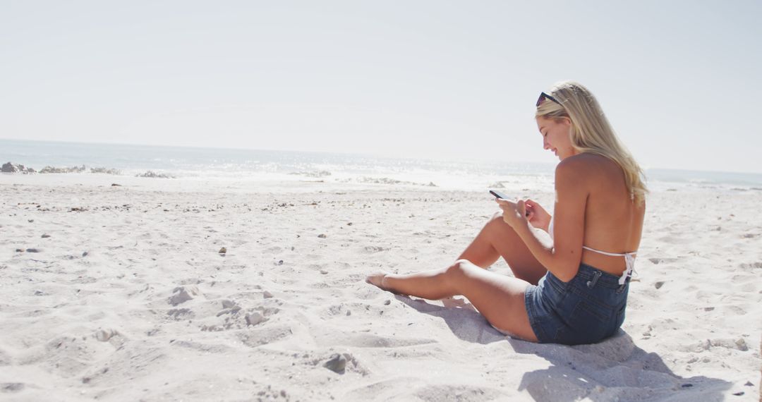 Woman Relaxing on Beach with Smartphone Enjoying Sunshine - Free Images, Stock Photos and Pictures on Pikwizard.com