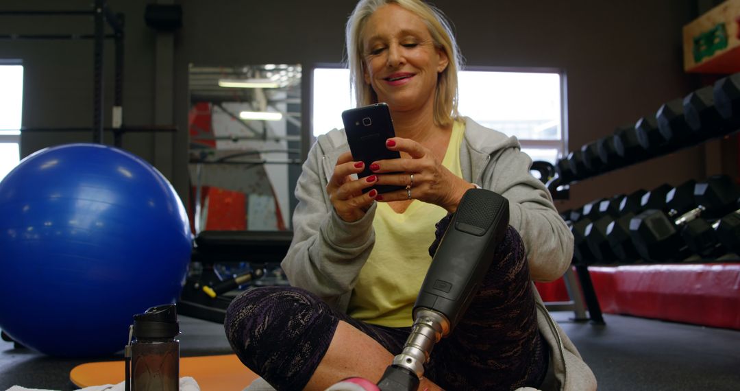 Amputee Woman Using Smartphone at Gym While Resting - Free Images, Stock Photos and Pictures on Pikwizard.com