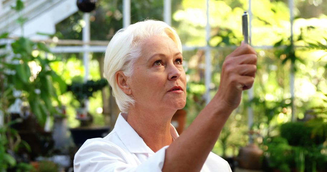 Female Botanist Examining Plant in Greenhouse Laboratory - Free Images, Stock Photos and Pictures on Pikwizard.com