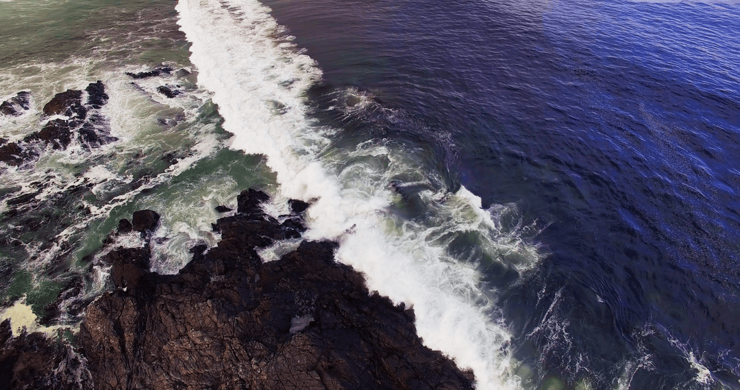 Transparent Waves Crashing Onto Rocky Shoreline from Above