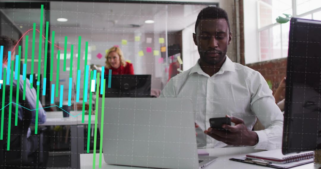 Checking smartphone while working on laptop in collaborative office with analytics overlay