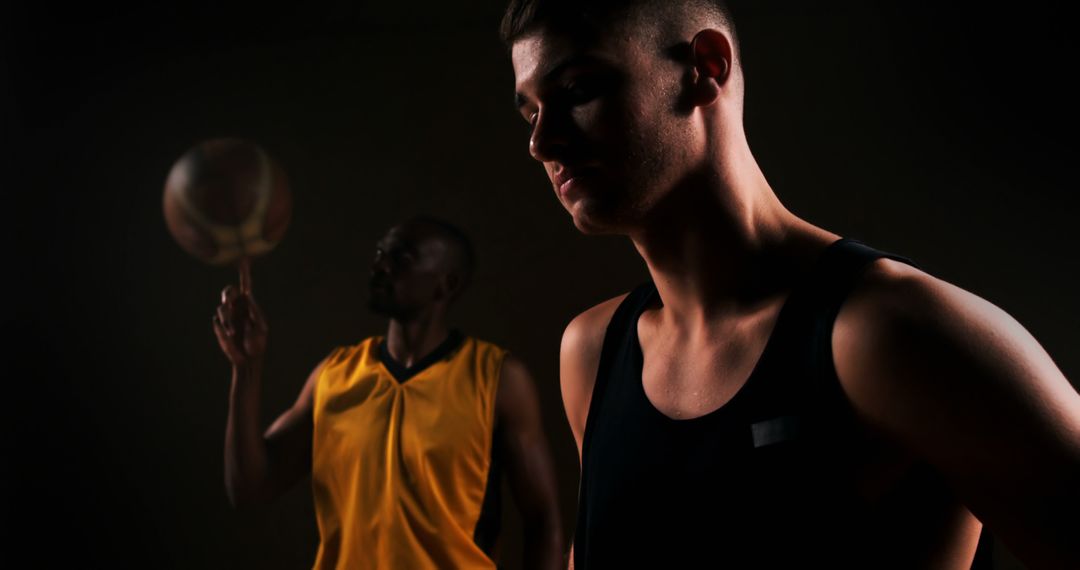 Focused Basketball Player with Opponent Spinning Ball in Dramatic Lighting