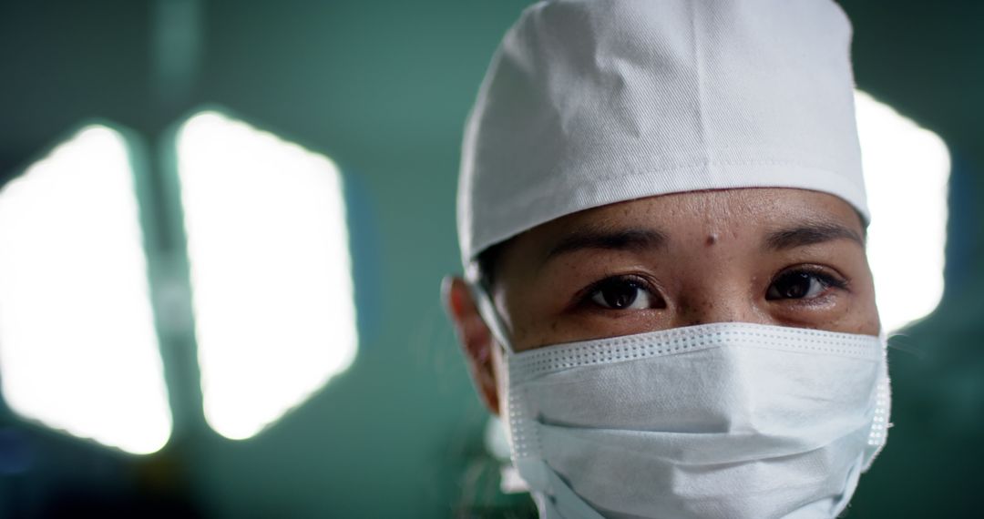 Closeup of Female Surgeon Wearing Surgical Mask with Medical Lights in Background - Free Images, Stock Photos and Pictures on Pikwizard.com