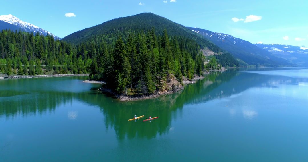 A person kayaks in a tranquil mountain lake, surrounded by lush forests, with copy space - Free Images, Stock Photos and Pictures on Pikwizard.com