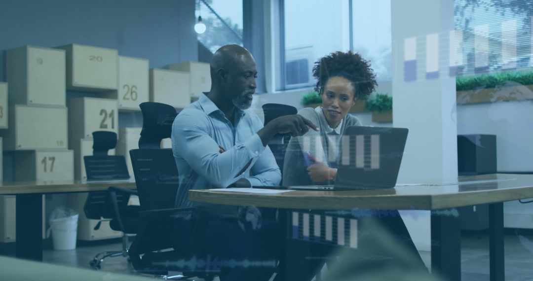 Diverse Team Evaluating Data Trends on Laptop in Modern Office