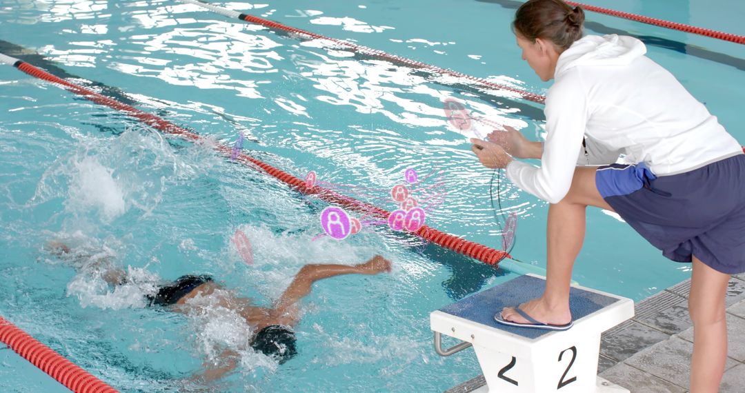 Coach timing swimmer sprinting in lane 2: stopwatch on starting block during indoor practice