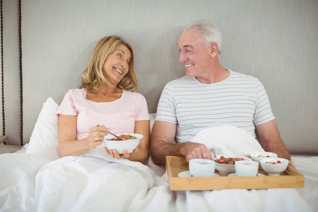 Smiling couple having breakfast on bed  - Free Images, Stock Photos and Pictures on Pikwizard.com