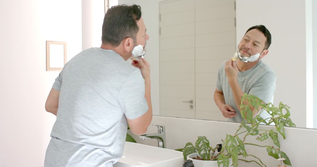 Mature Man Shaving with Razor in Bathroom Reflection
