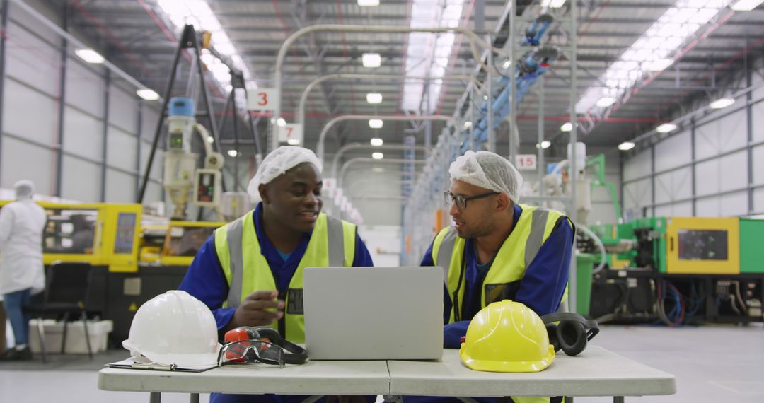 Industrial Engineers Discussing Work at Laptop in Manufacturing Factory - Free Images, Stock Photos and Pictures on Pikwizard.com