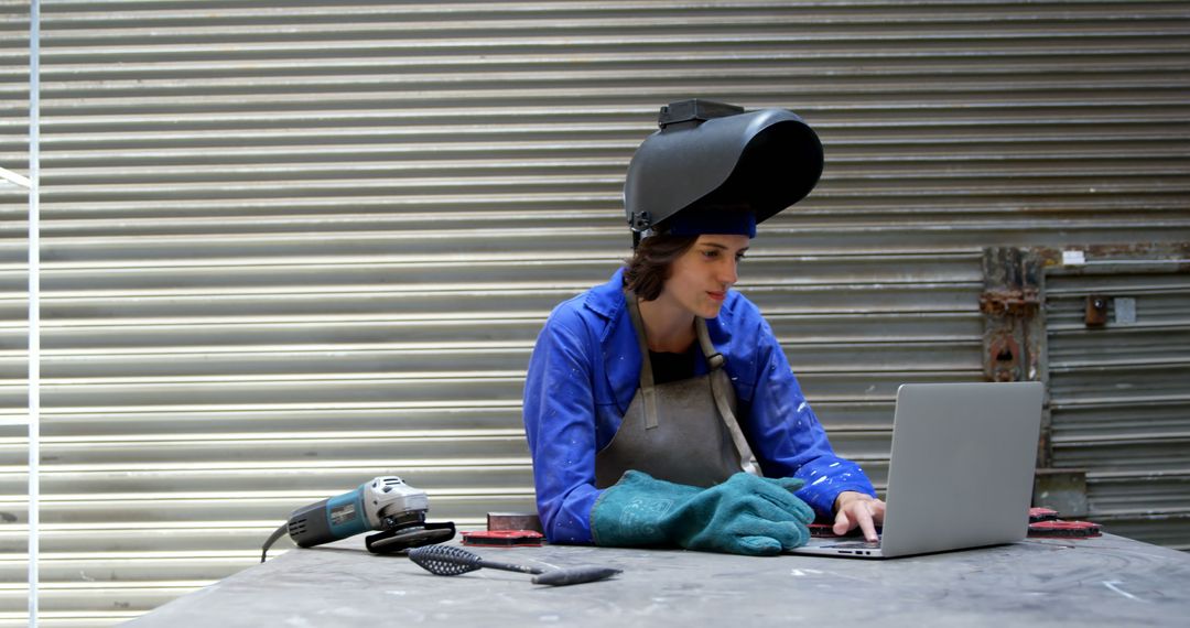 Female Welder Using Laptop in Workshop Wearing Protective Gear - Free Images, Stock Photos and Pictures on Pikwizard.com