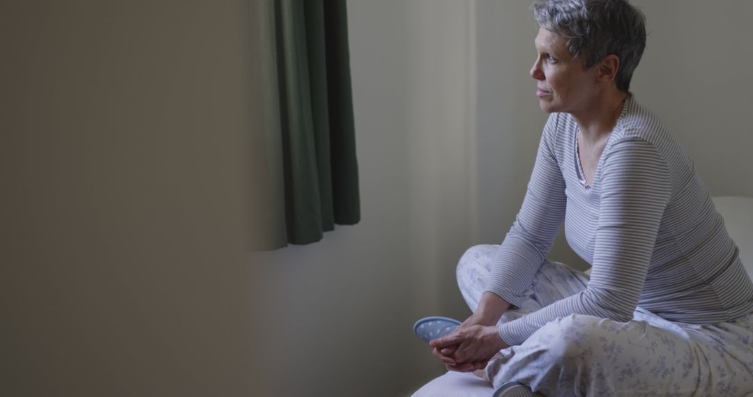 Reflective Older Woman Sitting in Bedroom in Pajamas - Free Images, Stock Photos and Pictures on Pikwizard.com