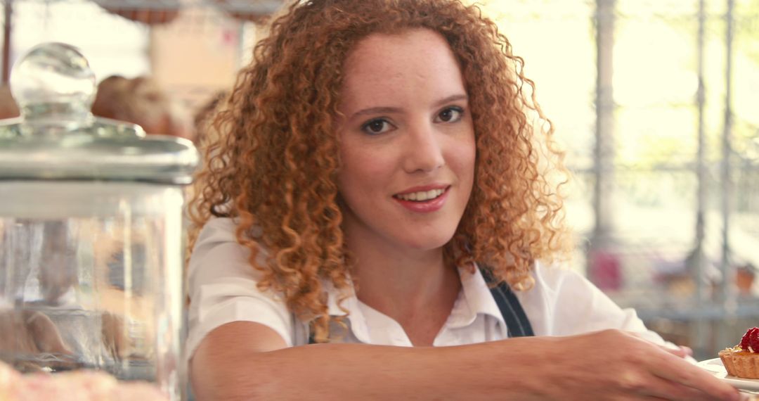 Smiling Female Baker in Cafe Holding Out Fresh Pastry - Free Images, Stock Photos and Pictures on Pikwizard.com