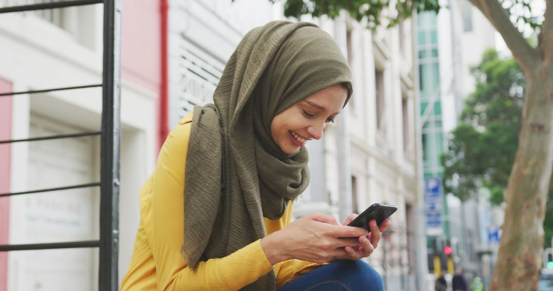 Smiling Muslim Woman Texting on Smartphone Outdoors in City, Wearing Hijab - Free Images, Stock Photos and Pictures on Pikwizard.com