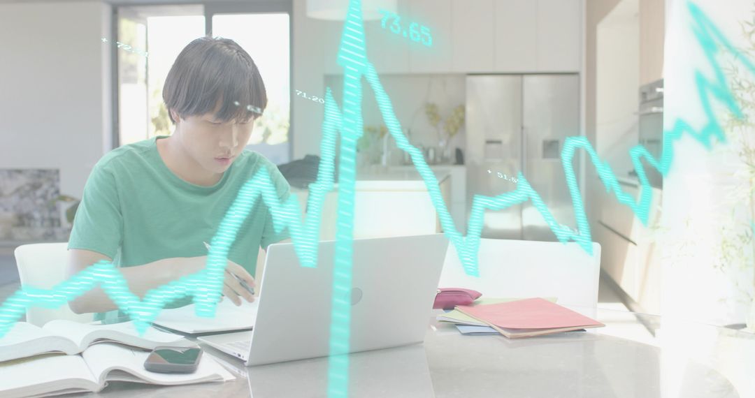 Young man working from home analyzing financial data on laptop in bright modern kitchen