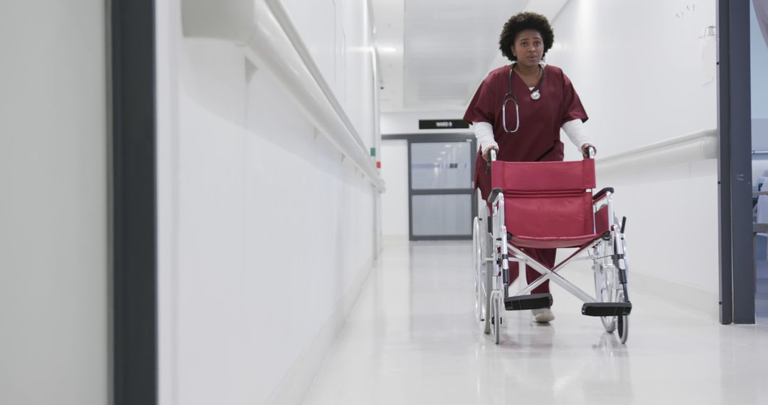 Healthcare professional walking down hospital hallway with wheelchair - Free Images, Stock Photos and Pictures on Pikwizard.com