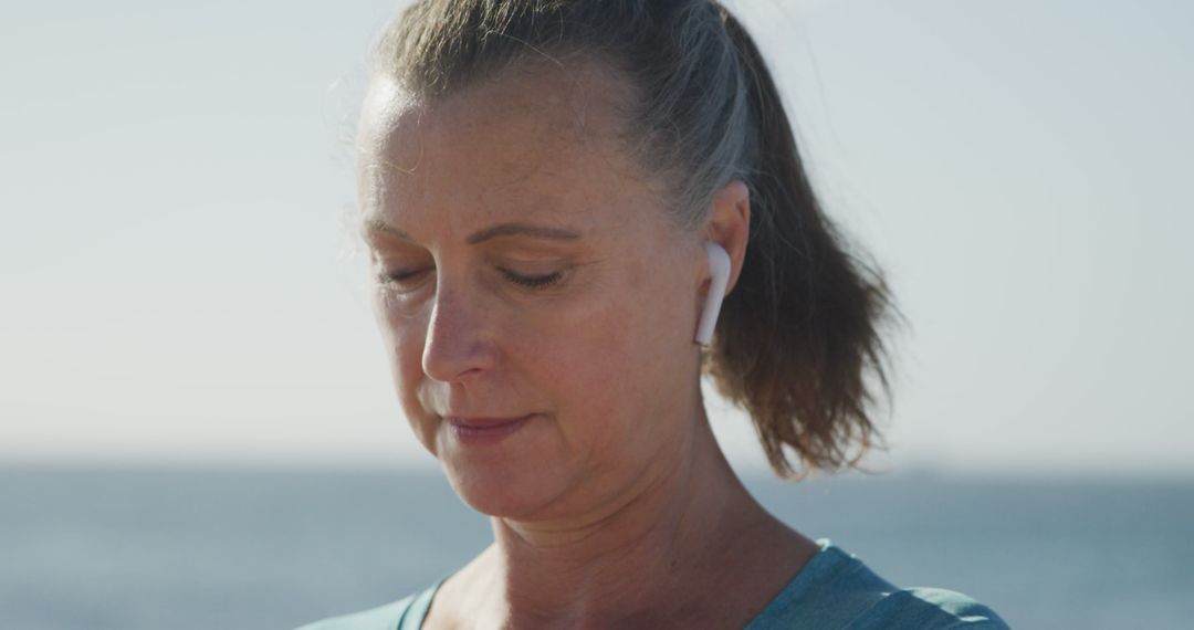 Senior Woman Enjoying Music with Wireless Earbuds Outdoors by the Sea - Free Images, Stock Photos and Pictures on Pikwizard.com