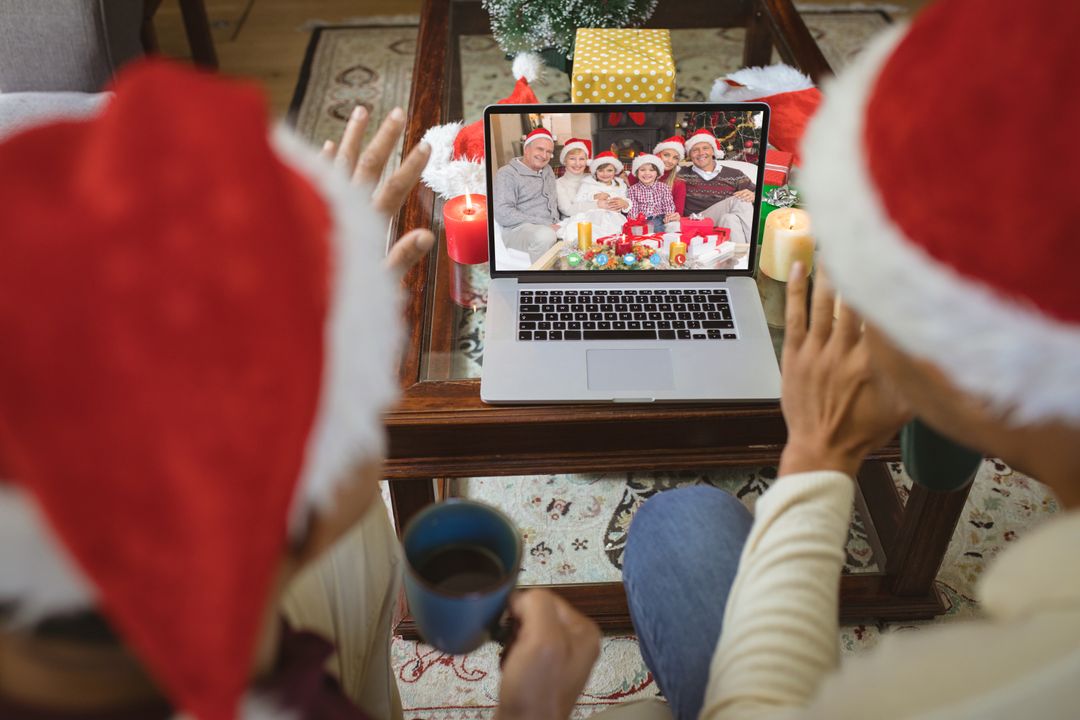 Diverse couple with santa hats having video call with happy caucasian family - Free Images, Stock Photos and Pictures on Pikwizard.com
