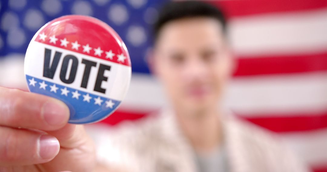 Man Holding Vote Button in Front of American Flag Promoting Elections