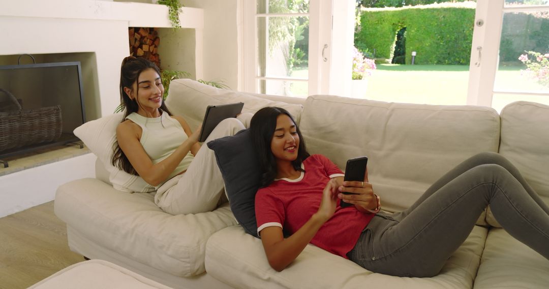 Diverse Friends Relaxing on Sofa with Gadgets in Modern Home