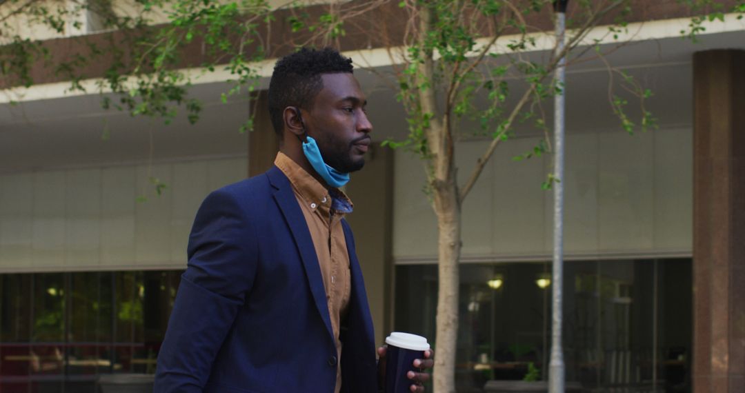 Businessman Holding Coffee Cup While Walking Outdoors - Free Images, Stock Photos and Pictures on Pikwizard.com