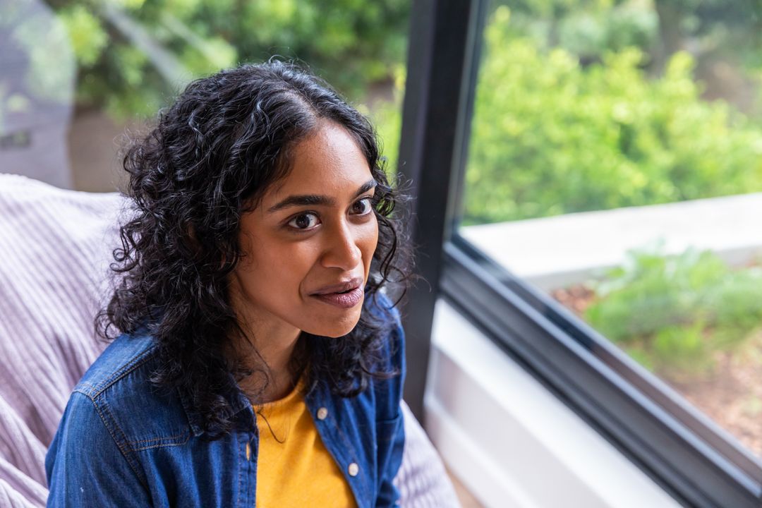 Woman Relaxing on Sofa with View of Lush Garden
