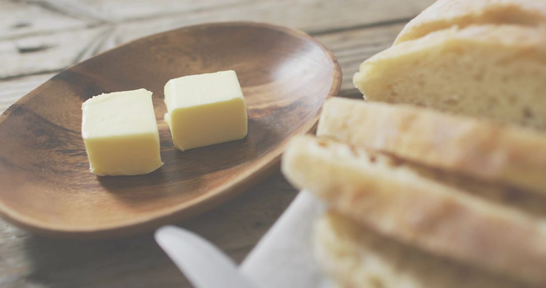 Two Butter Cubes Resting on Wooden Dish with Sliced Bread Rustic Breakfast Atmosphere