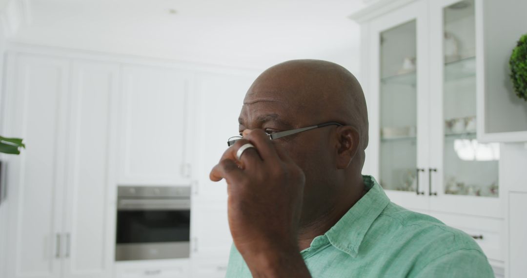 Senior Man in Kitchen Adjusting Glasses in Daylight - Free Images, Stock Photos and Pictures on Pikwizard.com