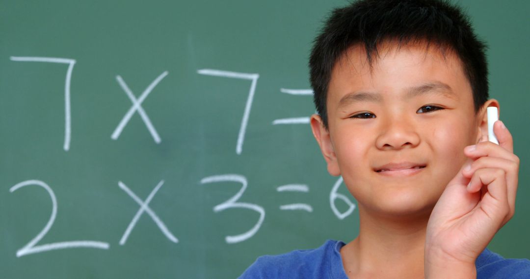 Smiling Asian Schoolboy Presenting Chalk in Classroom