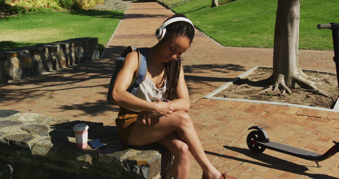 Young woman sitting on park bench listening to music with headphones - Free Images, Stock Photos and Pictures on Pikwizard.com