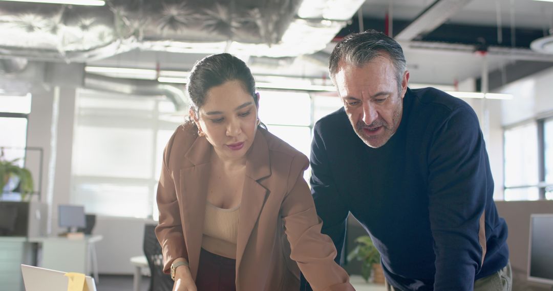 Professionals collaborating and reviewing strategy at laptop in modern open-plan office