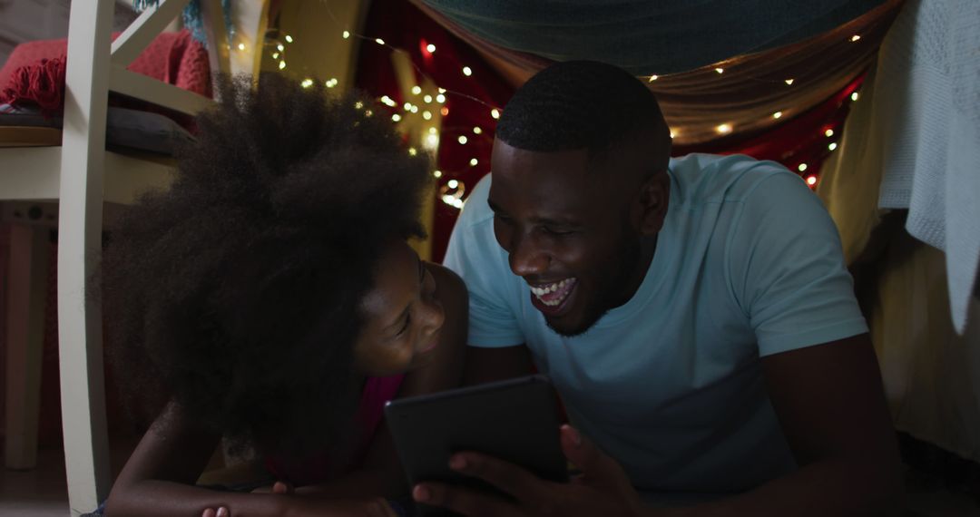 African American Father and Daughter Smiling While Reading Under Blanket Fort - Free Images, Stock Photos and Pictures on Pikwizard.com