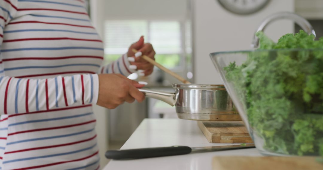 Person Wearing Stripes Preparing Meal Beside Kale Salad - Free Images, Stock Photos and Pictures on Pikwizard.com