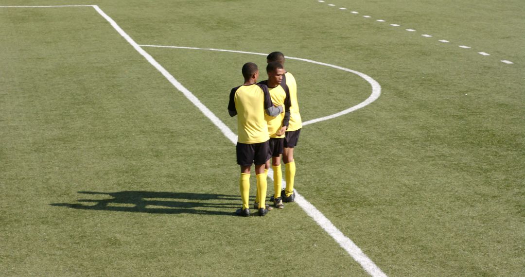 Soccer Players Strategizing on Field in Yellow Jerseys