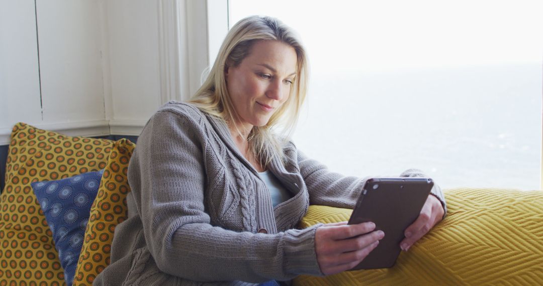 Woman Relaxing by Window with Tablet Device - Free Images, Stock Photos and Pictures on Pikwizard.com