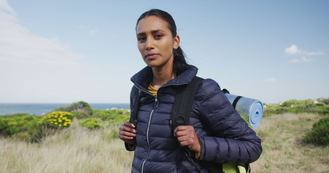 Woman Hiking with Backpack Across Scenic Countryside Landscape