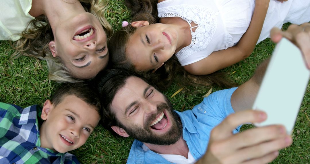 Happy Family Taking Selfie Lying on Grass Outdoors - Free Images, Stock Photos and Pictures on Pikwizard.com