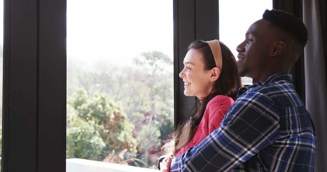 Diverse Couple Embracing and Smiling by Window