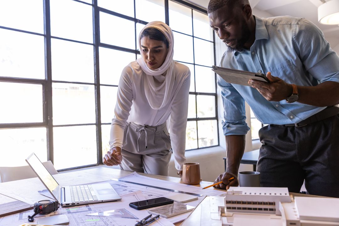 Diverse Professionals Reviewing Architectural Blueprints in Modern Office