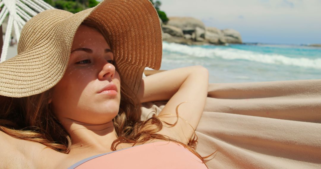 Woman Relaxing in Hammock by the Sea with Sunhat