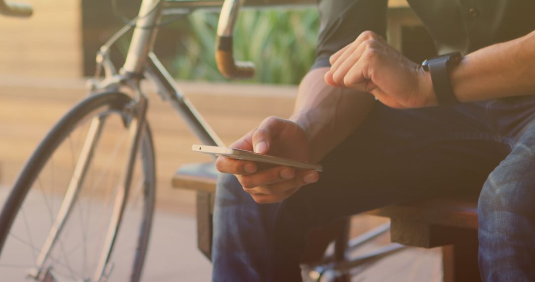 Man Relaxing with Smartphone Next to Bicycle
