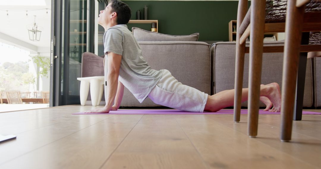 Young Man Practicing Yoga Cobra Pose at Home