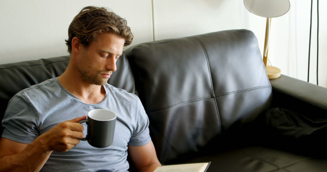 Man Reading Book with Coffee on Sofa in Living Room - Free Images, Stock Photos and Pictures on Pikwizard.com