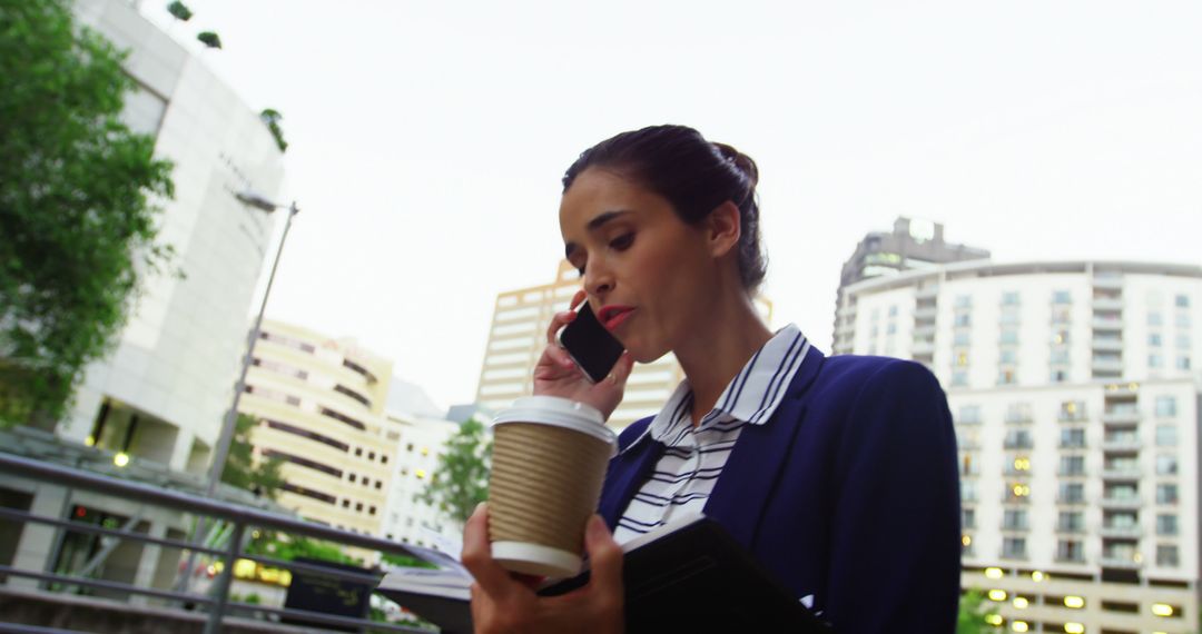 Businesswoman Talking on Phone Holding Coffee in Urban Setting - Free Images, Stock Photos and Pictures on Pikwizard.com