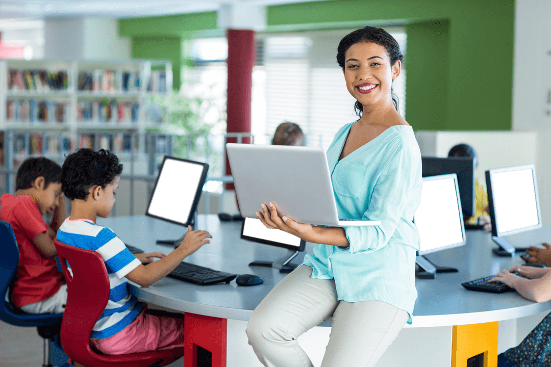 Young teacher holding laptop in modern classroom with students