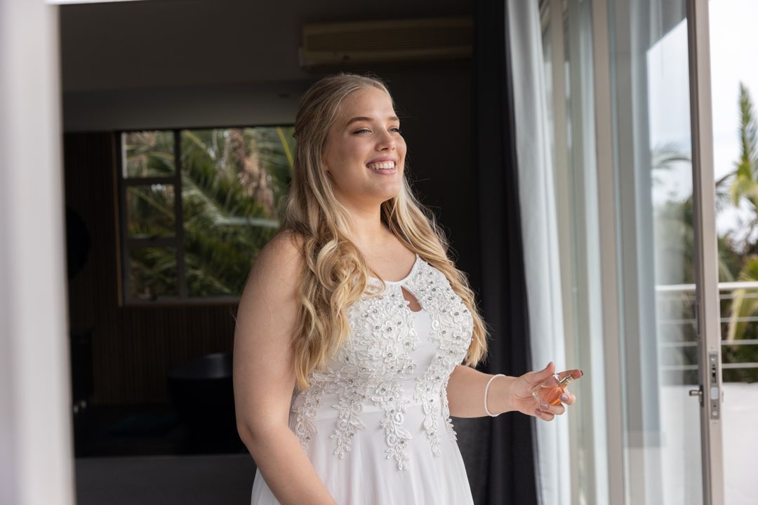 Bride in Elegant Gown Applying Perfume in Wedding Suite