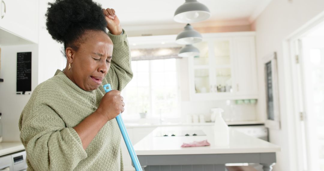 Woman singing into mop handle while cleaning kitchen - Free Images, Stock Photos and Pictures on Pikwizard.com