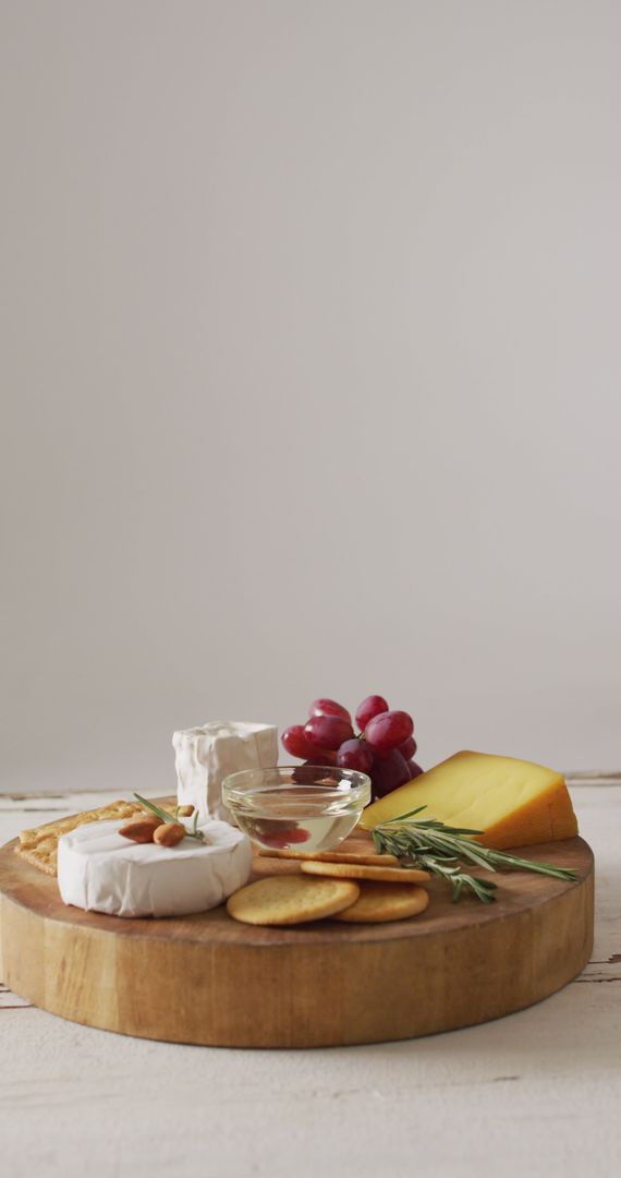 Assorted Cheeses with Biscuits and Grapes on Rustic Board