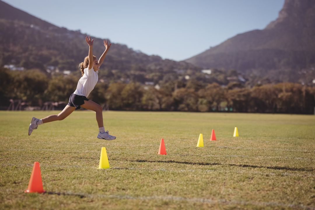 Child Exercising on Field Jumping Over Training Cones Outdoors